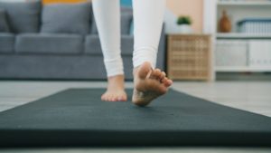Low shot slow motion of a woman rolling out yoga mat then working out in plank position
